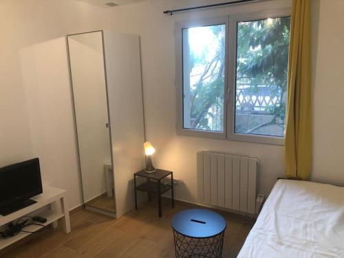 une chambre avec un lit, une télévision et une fenêtre dans l'établissement Cosy studio, à Saint-Denis
