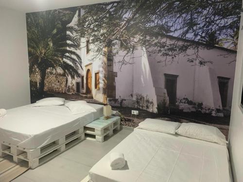 two beds in a room with a mural on the wall at Palmira House in Cidade Velha