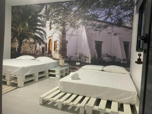 two beds in a room with a mural on the wall at Palmira House in Cidade Velha