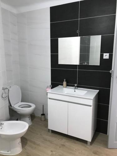 a bathroom with a white toilet and a sink at Casa do Balcão in Meda