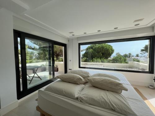 a bedroom with large windows and a bed with pillows at Preciosa Villa en Siesta in Santa Eularia des Riu