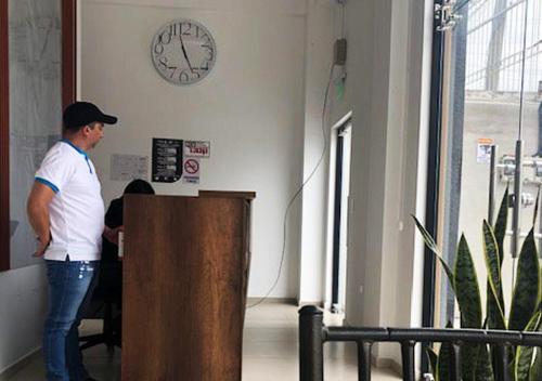 a man standing at a podium in a room with a clock at Hotel Suites La Fontana in Ambato