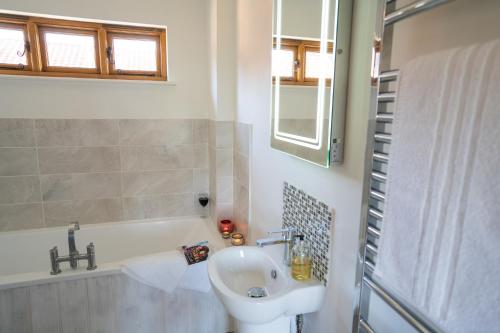 a bathroom with a sink and a bath tub at The Granary at Red House Farm in Stradbroke