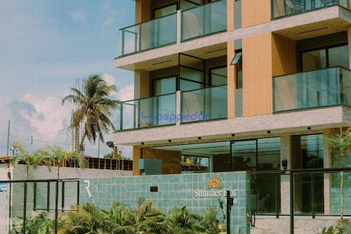un bâtiment avec des fenêtres en verre et un palmier dans l'établissement Summer by Hosppedar, à Cabedelo