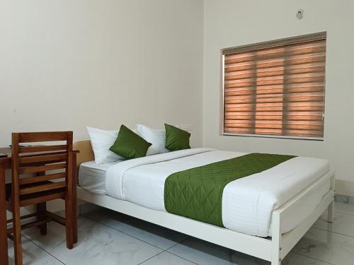 a bedroom with a bed and a desk and a window at Greenview Royal Stay Near Amrita Hospital Edappally in Cochin