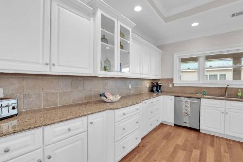 a white kitchen with white cabinets and wooden floors at 5 Bed 5 Bath Luxury Beach Front Home w/Ocean Views in Tybee Island