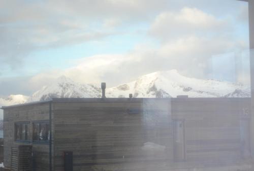 a snow covered mountain in the distance with a building at High end cabin with Jacuzzi in Lyngværet