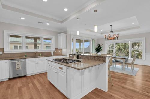 a large kitchen with white cabinets and a table at 5 Bed 5 Bath Luxury Beach Front Home w/Ocean Views in Tybee Island