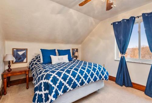 a bedroom with a blue and white bed and a window at Cheerful 4BR Chalet with Seasonal Pool, Hot Tub in New Kensington