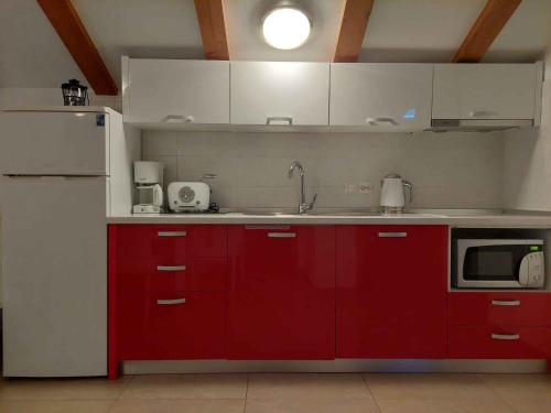 a kitchen with red cabinets and a white refrigerator at Apartment Ljubac 3 in Ljubač