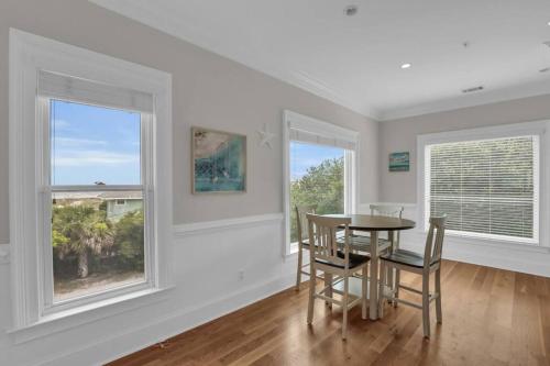 a dining room with a table and two windows at 5 Bed 5 Bath Luxury Beach Front Home w/Ocean Views in Tybee Island