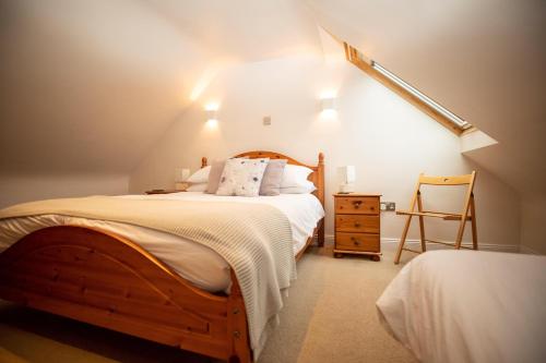a bedroom with a wooden bed and a chair at Purves Cottage in Allanton