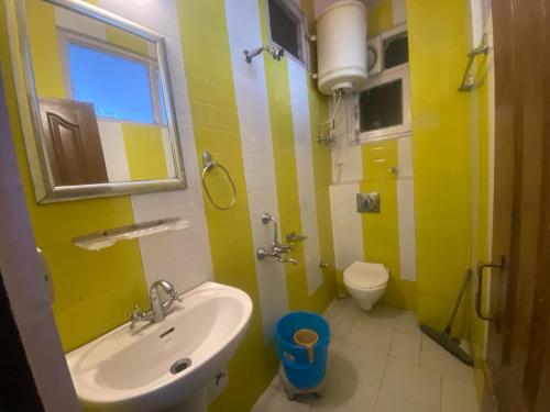 W łazience w kolorze żółtym i białym znajduje się umywalka i toaleta. w obiekcie BNB ROYAL INN SHIMLA w mieście Shimla
