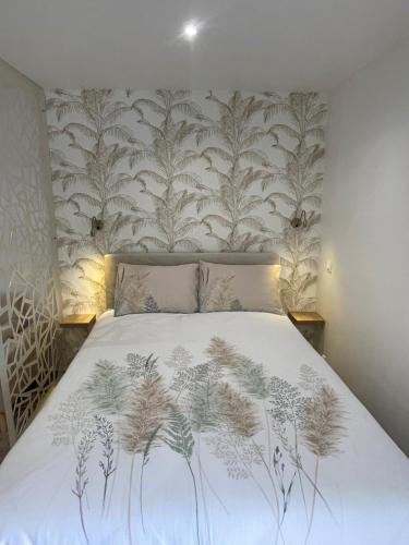 une chambre avec un lit avec un papier peint fleuri dans l'établissement Studio entre mer et centre-ville, à Dunkerque