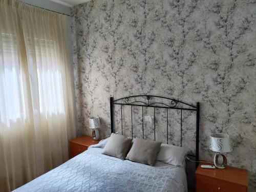 1 dormitorio con cama y pared con papel pintado en San Miguel, en Membrilla