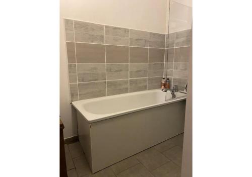baño con bañera blanca y azulejos en Chambre tropicale privée, en Liévin