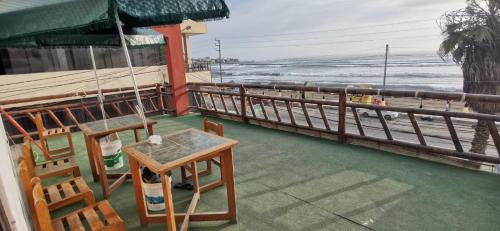 een veranda met een tafel en stoelen en het strand bij HOSTAL EL REFUGIO in Huanchaco