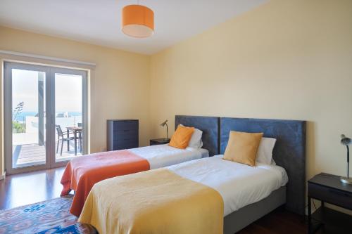 two beds in a room with a balcony at Casa dos Ciprestes in Ericeira