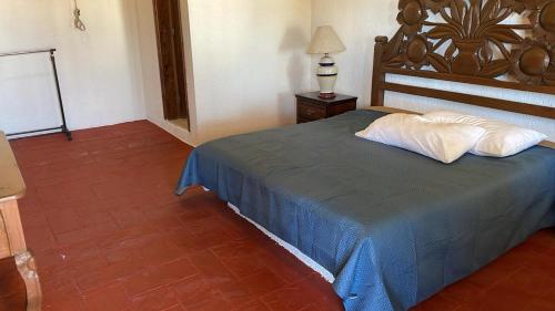 um quarto com uma cama com um cobertor azul e almofadas brancas em Hotel Terraza Los cabos em Cabo San Lucas