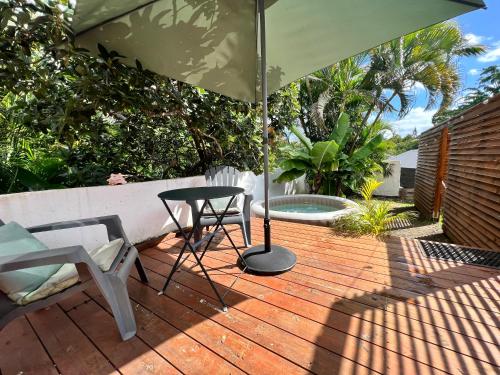 un patio con sombrilla, mesa y silla en Bungalow cosy près des plages en Le Gosier