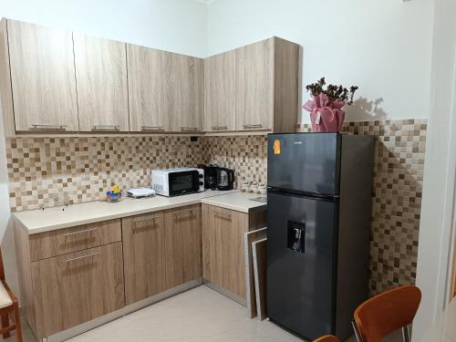 uma cozinha com um frigorífico preto e armários de madeira em Your Athens home em Atenas