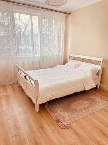 a white bed in a bedroom with a window at Cozy apartment in Galati in Galaţi
