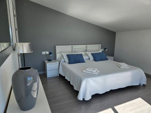 een slaapkamer met een groot wit bed met blauwe kussens bij FANTÁSTICO DÚPLEX CON VISTAS IMPRESIONANTES AL MAR in Peñíscola