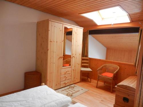 a bedroom with a bed and a cabinet and a chair at Appartement Bergfrieden in Oberstaufen
