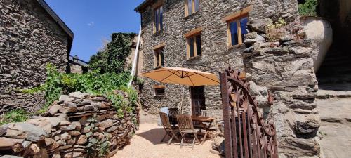 une table avec un parasol devant un bâtiment en pierre dans l'établissement Mountain Village Studio en Nohèdes pour 2, à Nohèdes