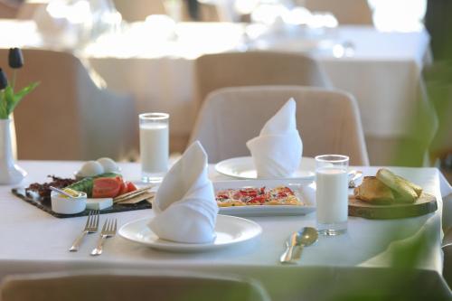 a white table with plates of food and napkins at Blue Bay Residence in Vlorë