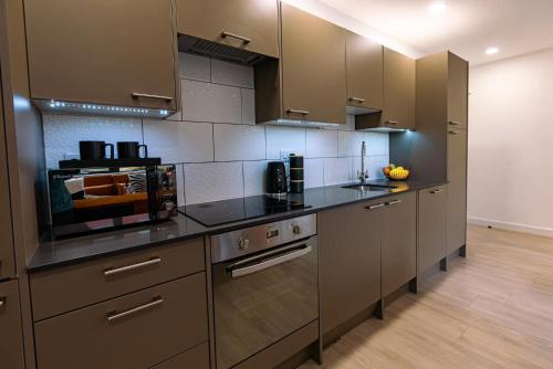 a kitchen with stainless steel appliances and brown cabinets at Modern City Centre Apartment in Exeter
