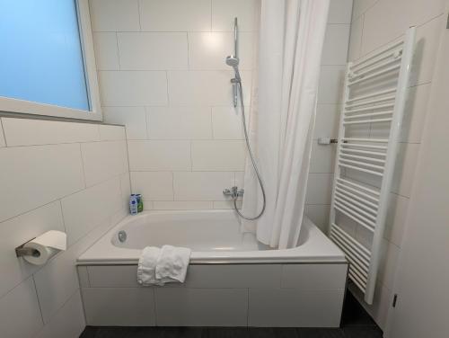 y baño con bañera y cortina de ducha. en 100m zum Ulmer Münster: 57m² Wohnung an der Blau, en Ulm