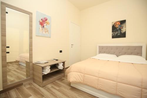 a white bedroom with a bed and a mirror at Blue Bay Residence in Vlorë