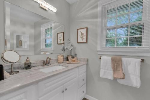 a white bathroom with a sink and a mirror at Mayfair Hideaway: 3 Bed 2 Bath Savannah BnB in Savannah