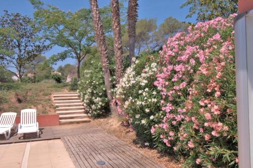 - un jardin avec 2 chaises et des fleurs roses dans l'établissement Studio Albatros en RDJ avec Terrasse, Parking privé, Piscine, proche Golf St Donat, à Mouans-Sartoux