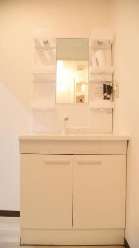 a white bathroom with a sink and a mirror at Osaka Shinsaibashi Dotonbori Courtyard Villa in Osaka