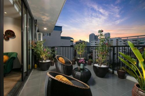a balcony with chairs and potted plants on a balcony at The Bloom Hanoi - Bespoke Living in Hanoi