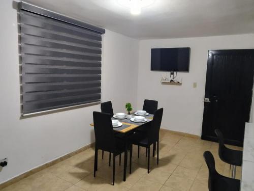 a dining room with a table and chairs and a tv at Depa Eco en planta baja, a 5 minutos del malecon y zona dorada in Mazatlán