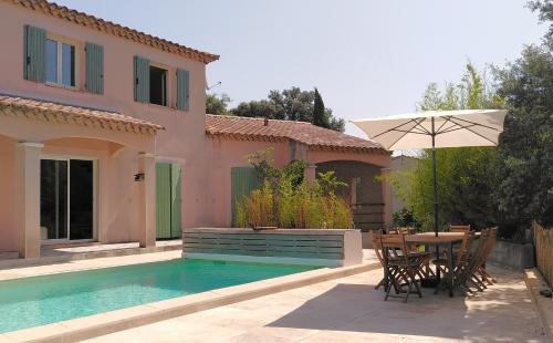 - une terrasse avec une table et un parasol à côté d'une maison dans l'établissement Belle villa proche Uzès, à Vallabrix