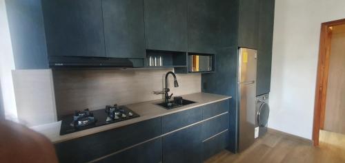 a kitchen with black cabinets and a sink and a refrigerator at Dpto independiente Puerto Ayora - Galápagos in Puerto Ayora