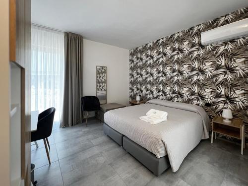 1 dormitorio con cama y pared con papel pintado frondoso en Pinea b&b en Castellaneta Marina 