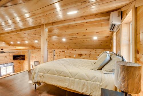 ein Schlafzimmer mit einem Bett in einem Zimmer mit Holzwänden in der Unterkunft Friends and Family Rental Cabin with Hot Tub! 