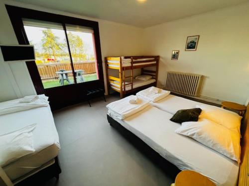 a bedroom with two beds and a large window at HOSTEL Les Bois Verts - Les Herbiers in Les Herbiers