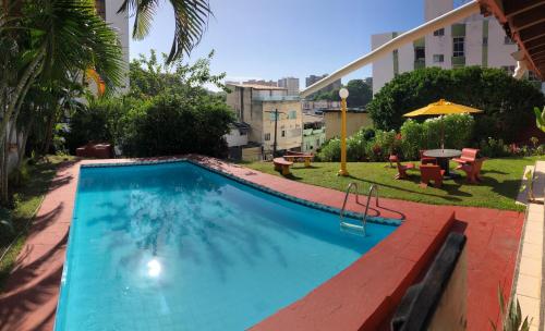 a swimming pool in a yard with a table and umbrella at Point do Rio Vermelho in Salvador