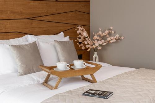 a tray with two coffee cups on a bed at Hotel Biogor Wellness & Spa in Sisevac