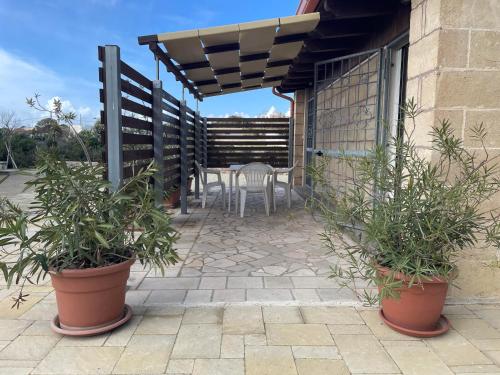 a patio with a table and chairs and plants at Villetta La Lama in Torre Lapillo