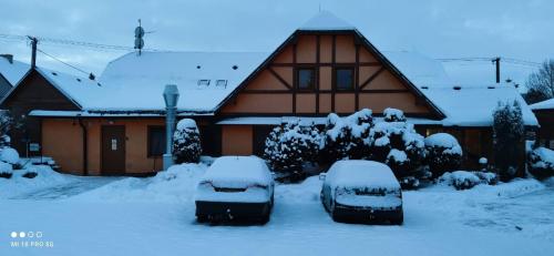 two snow covered cars parked in front of a house at Penzion U Kata in Bruntál