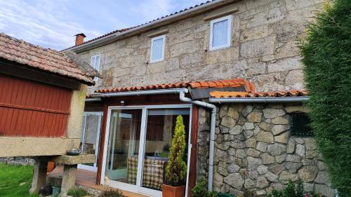 een stenen huis met een glazen schuifdeur bij A Leiriña - Casa rural para desconexión in La Cañiza