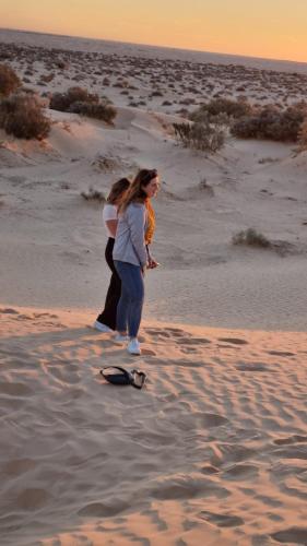 two women standing on a beach with a skateboard at Private Camp25km-from DOUZ in Douz