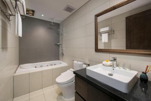 a bathroom with a sink and a toilet and a tub at The Bloom Hanoi - Bespoke Living in Hanoi